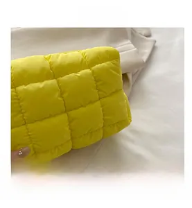 Detailed close-up of the quilted yellow nylon bag texture and puffer fabric stitching