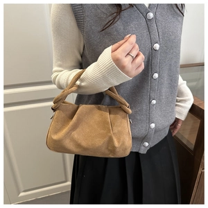 Detail of a brown faux suede dumpling bag with pleated texture and knotted handle