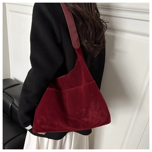 Gros plan d'un sac cabas en daim bordeaux avec large bandoulière et texture mate chic
