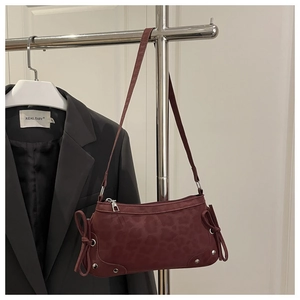 Detail of burgundy leopard embossed bag with side bows and silver rivet accents