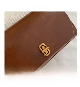 Close-up of brown vintage leather texture and antique gold metal rectangular twist lock