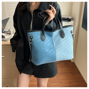 Detail of color-block denim tote bag with black leather edges and fine stitching accents