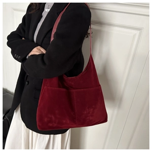 Détail d'un sac hobo en daim rouge avec poches avant et large bandoulière porté