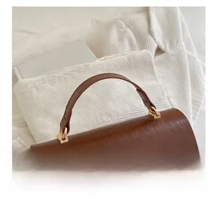 Detail of vintage brown leather handbag handle with sturdy gold metal hardware connectors
