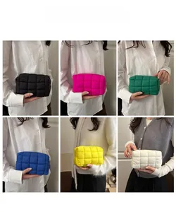 Detailed view of quilted puffer cosmetic bags in various colors held by a model