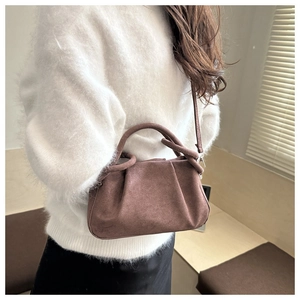 Close-up of minimalist brown suede cloud bag with soft pleats and elegant handles
