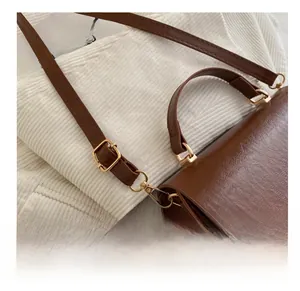 Detail of adjustable gold buckle on the brown leather strap of this square bag