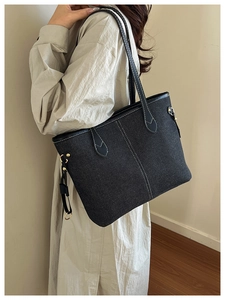 Detail of dark grey denim tote bag featuring white contrast stitching and gold hardware