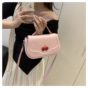 Pink saddle-shaped crossbody bag with decorative red 3D cherry pendants on flap