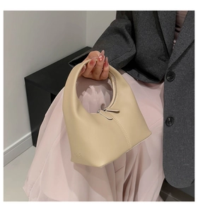 Detail of hobo bag with dual zipper closure and vertical stitching on beige faux leather