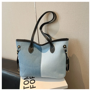 Detail of color-block denim tote bag showing fabric texture and leather strap