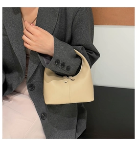 Chic beige mini handbag detail held by model with minimalist stitching and sleek design