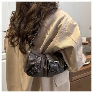 Detail of dark brown pleated shoulder bag with vintage metal buckle on a beige coat