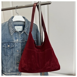 Détail du sac hobo bordeaux en daim avec couture centrale et bandoulière en cuir lisse
