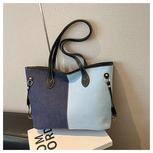 Close-up of contrast canvas tote bag featuring premium leather trim and gold metal hardware