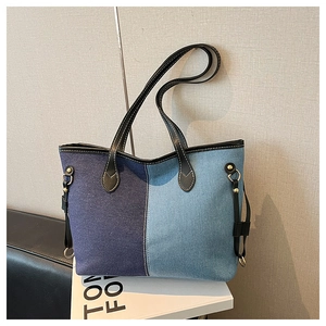 Detail of color-block denim tote bag with leather straps and gold-tone hardware