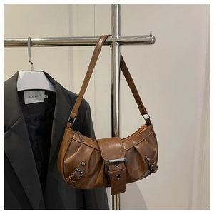 Close-up of brown pleated underarm bag featuring vintage metal buckle and leather texture