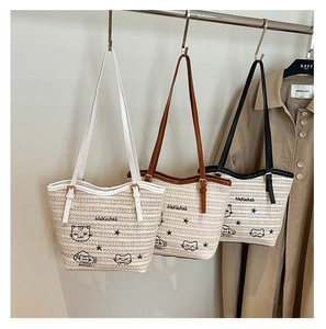 Détail de sacs cabas en paille tissée avec broderie chat en blanc, marron et noir