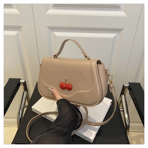 Detail of khaki square bag with 3D red cherry decoration and gold hardware hooks