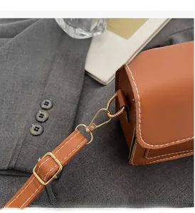 Detail of brown leather bag showing white contrast stitching and gold metal hardware