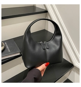 Detail of minimalist black crescent bag with fine leather texture and metallic zippers