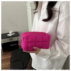 Detailed shot of quilted nylon toiletry bag in vibrant magenta with gold zipper pull