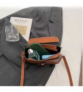 Detail view of the brown leather crossbody bag interior showing phone and perfume