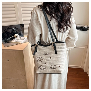 Détail du cabas tissé crème avec broderie de chat et anses en cuir noir dans un cadre de vie moderne