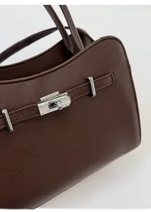 Close-up of silver twist lock and lychee texture on dark brown leather handbag