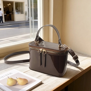 Chic brown patent leather vanity box bag with gold hardware on a wooden table