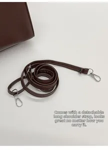 Detail of dark brown lychee leather shoulder strap with silver metal swivel hooks
