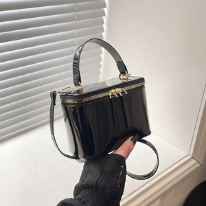 Minimalist black patent leather vanity box bag with gold zippers and a detachable strap
