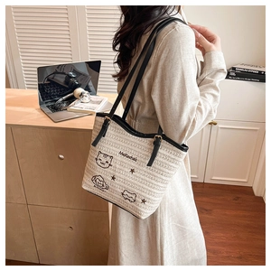 Détail du sac cabas tissé avec broderie chat cartoon et bandoulière en cuir noir