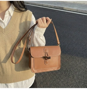 Detail of vintage brown shoulder bag showing a toggle button and stitching on faux leather