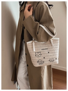 Détail du sac cabas tressé beige avec broderie chat et bandoulières blanches contrastées
