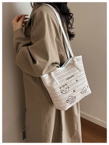 Modèle portant un sac cabas tressé crème avec broderie chat et bandoulière élégante