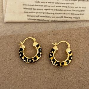 Detail shot of vintage leopard print enamel gold hoop earrings on a retro background
