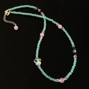 Light green crystal bead necklace with iridescent butterfly pendant on black background