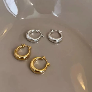Polished gold and silver thick hoop earrings set on a minimalist aesthetic display
