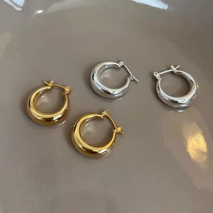 Close-up of chunky gold and silver plated hoop earrings on a ceramic background