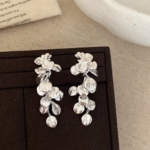 Silver leaf tassel earrings with irregular metallic petals on a jewelry display board
