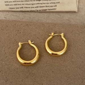 Polished thick golden hoop earrings for women in a minimalist luxury round design