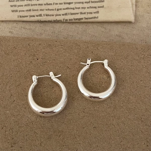 Elegant silver hoop earrings with a polished mirror finish on a warm vintage background