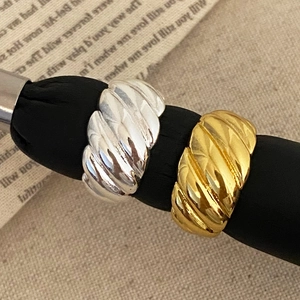 Polished gold and silver croissant dome rings set on a textured beige fabric backdrop