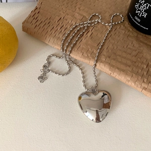 Collier élégant avec pendentif cœur argenté et chaîne à billes sur fond esthétique épuré