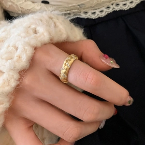 Gros plan d'une bague dorée à texture tissée avec zircons brillants sur une main