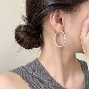 Detailed macro view of silver double-layered hoop earrings with polished and textured finish