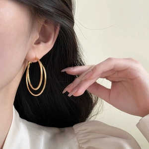 Close-up of gold double-layer hoop earrings featuring frosted and polished metallic textures