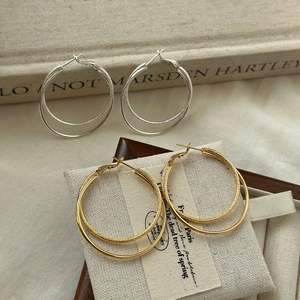 Close-up of dual-layer hoop earrings in gold and silver with polished and frosted textures