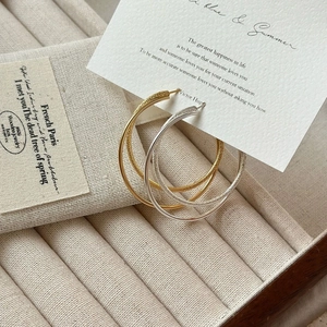 Detailed view of large matte textured hoop earrings in gold and silver finish